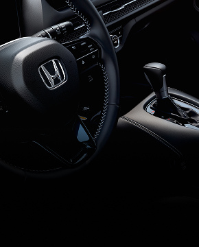 Honda steering wheel with contrast stitching and gear shift console.