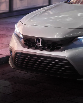 2024 Honda Civic Sedan Touring in Lunar Silver Metallic front parked on a city street at night (Compact Sedan).