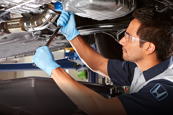 Honda service technician working on the undercarriage.