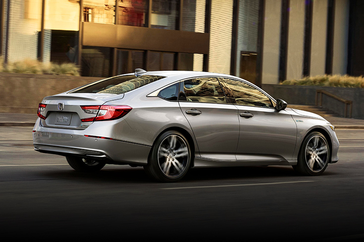 2022 Honda Accord Hybrid Touring in Lunar Silver Metallic back driving on a city street (Mid-Size Sedan).